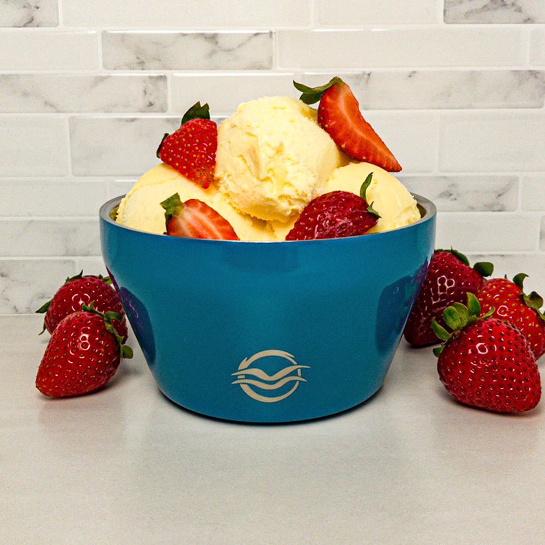 Blue Calicle vacuum insulated ice cream bowl filled with vanilla ice cream topped with fresh strawberries